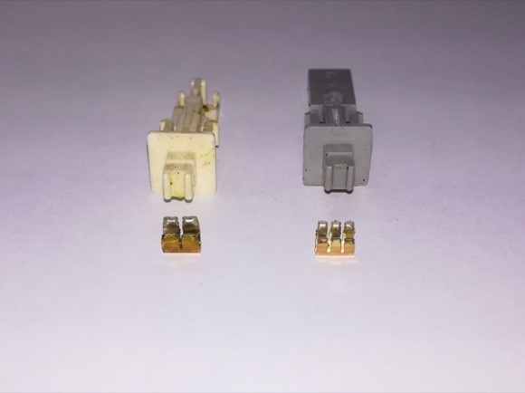 Aus diesen Teilen des alten Schalters, wird der Adapter für die Tastenkappe hergestellt. Auf dem Foto ist zu erkennen, Weiß und Grau haben unterschiedliche Kontakte gehabt - vor den beiden Kunststoffteilen liegen  alte Kontaktteile.