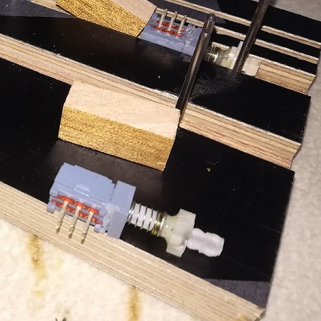 Wenn ein Adapter verloren ist, dann selbst einen fertigen, z. B. aus einem Plexiglasstreifen 8x8 mm, daraus gesägt/gefeilt einen Adapter (vorne im Foto). War schnell hergestellt... Hier ist kein ALPS Schalter sondern ein  PS909-22 Miniaturschalter verklebt worden. Für den Halt auf den Winkel, habe ich eine leichte Nut gesägt – Kontaktseite vorne.